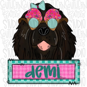 May include: A black dog with ice cream cones on its eyes and a blue bow on its head. The dog is looking at the camera and has its tongue sticking out. The dog is holding a sign that says "demi" in teal letters on a pink and teal checkered background.