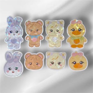 May include: Set of eight iridescent holographic stickers featuring cute cartoon animals. The animals include a bunny, a bear, a cat, and a duck. The stickers are perfect for adding a touch of whimsy to your planner, laptop, or phone.