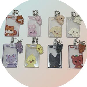 May include: Eight clear plastic keyrings featuring cartoon animal charms, including a tiger, bunny, dog, cat, bear, and chick. Each keyring has a silver-coloured ring.
