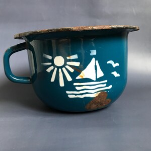 Op de afbeelding: Een tealblauwe emaille kamerpot met een wit zeilboot-, zon- en meeuwenontwerp.