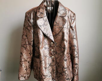 Könnte beinhalten: Ein gold- und braunes gemustertes Blazer mit einem einzigen Knopfverschluss. Der Blazer hat einen Kragen und lange Ärmel.