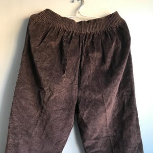 May include: Brown corduroy pants with a wide waistband and a relaxed fit.