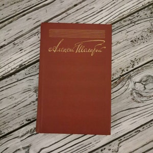 May include: A red hardcover book with gold lettering on the spine that reads "Aleksandr Solzhenitsyn".