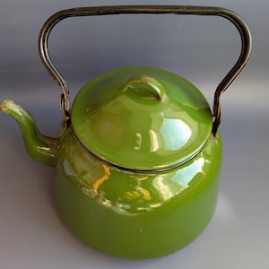 Peut inclure: Une théière vintage en émail vert avec une poignée et un couvercle en métal courbé. La théière a un bec verseur et un corps arrondi. La poignée est fixée sur les côtés de la théière. La théière est de couleur vert vif.