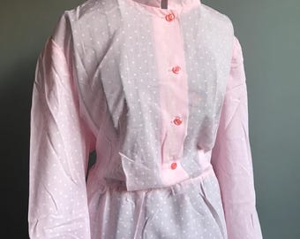 Könnte beinhalten: Ein rosa Kleid mit weißen Punkten, einem weißen Kragen und langen Ärmeln. Das Kleid hat einen Knopfleisten vorne und eine taillierte Passform.