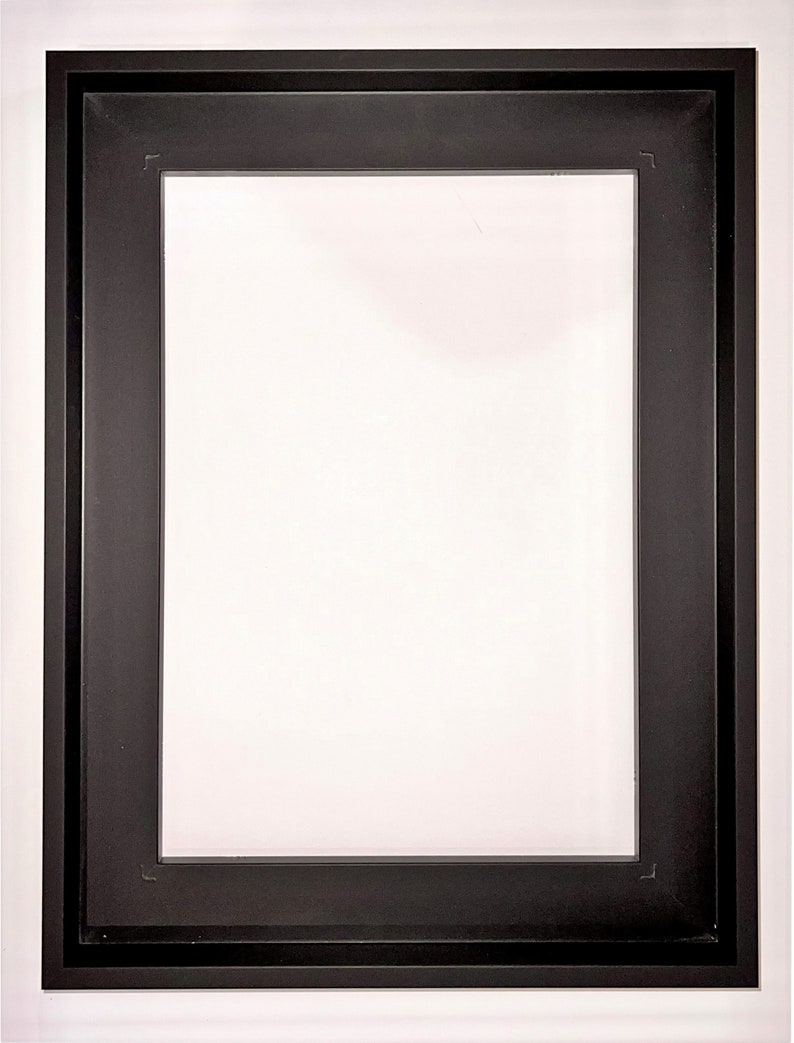 May include: A black picture frame with a white mat and a white outer frame.