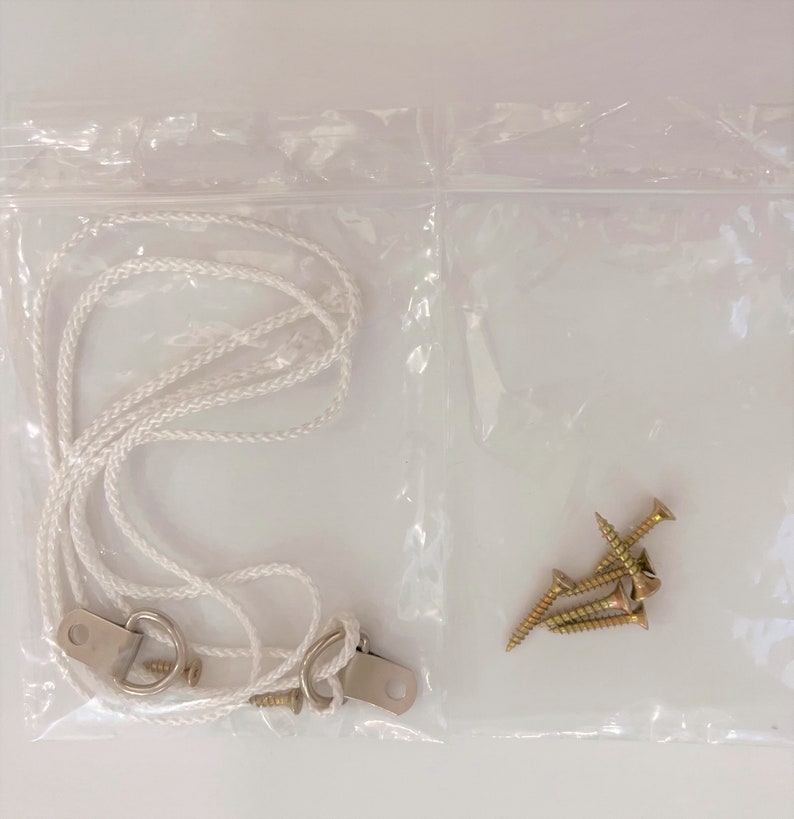 May include: A clear plastic bag containing a white rope, two metal hooks, and four gold screws.
