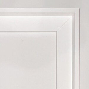 May include: A white picture frame with a simple, clean design. The frame has a slightly raised edge around the perimeter.