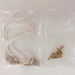 May include: A clear plastic bag containing a white rope, two metal hooks, and four gold screws.