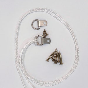 May include: A set of two silver D-rings with a white rope and six gold screws. The D-rings are used for hanging items.