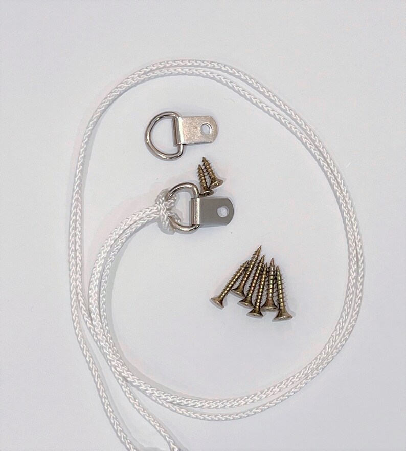 May include: A set of two silver D-rings with a white rope and six gold screws. The D-rings are used for hanging items.