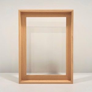 May include: A natural wood picture frame with a simple design. The frame is made of solid wood and has a smooth finish.