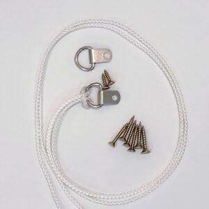 May include: A set of two silver D-rings with a white rope and six gold screws. The D-rings are used for hanging items.