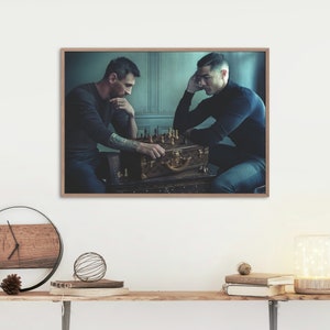 Op de afbeelding: Ingelijste print met twee mannen die schaken. Het schaakspel staat op een vintage bruine koffer. De mannen dragen donkere kleding, &eacute;&eacute;n man heeft een volledige mouwtattoo. De achtergrond is een gedempt blauw.