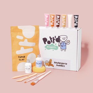 May include: A craft kit for making clay bread. The kit includes a bag of clay, six tubes of paint, two bottles of glaze, a sponge, four paintbrushes, and a box with the text "Pottery Projects" and "Boulangerie Buddies".