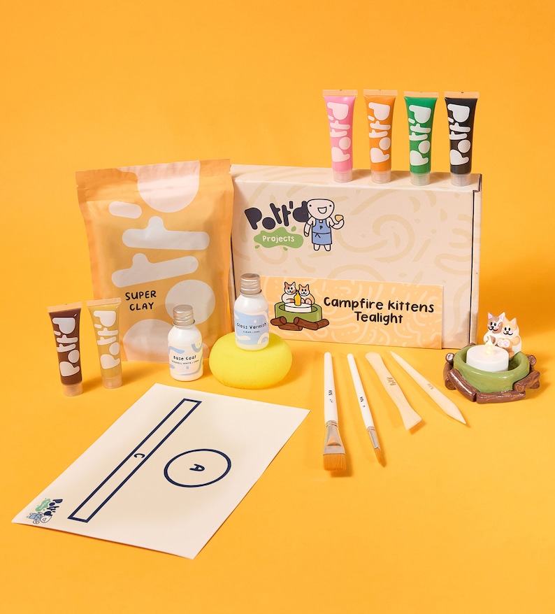 May include: A craft kit for making a tealight with a campfire kitten design. The kit includes clay, paint, brushes, and a tealight holder. The box is labeled "Campfire Kittens Tealight" and "Polito Projects".