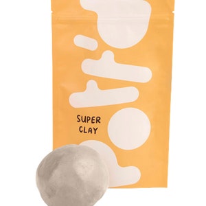 Könnte beinhalten: Eine graue Kugel aus Super Clay in einem gelben Beutel mit weißen abstrakten Formen und dem Text "SUPER CLAY".