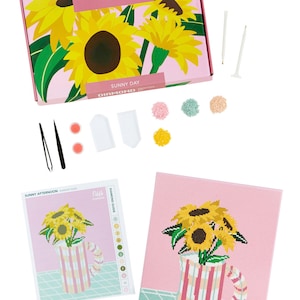 Może przedstawiać: R&oacute;żowe pudełko z wzorem słonecznika i tekstem "Dabble Diamond Painting Kit" i "Sunny Day". Pudełko zawiera pł&oacute;tno, narzędzia i diamentowe koraliki do projektu malowania diamentowego.