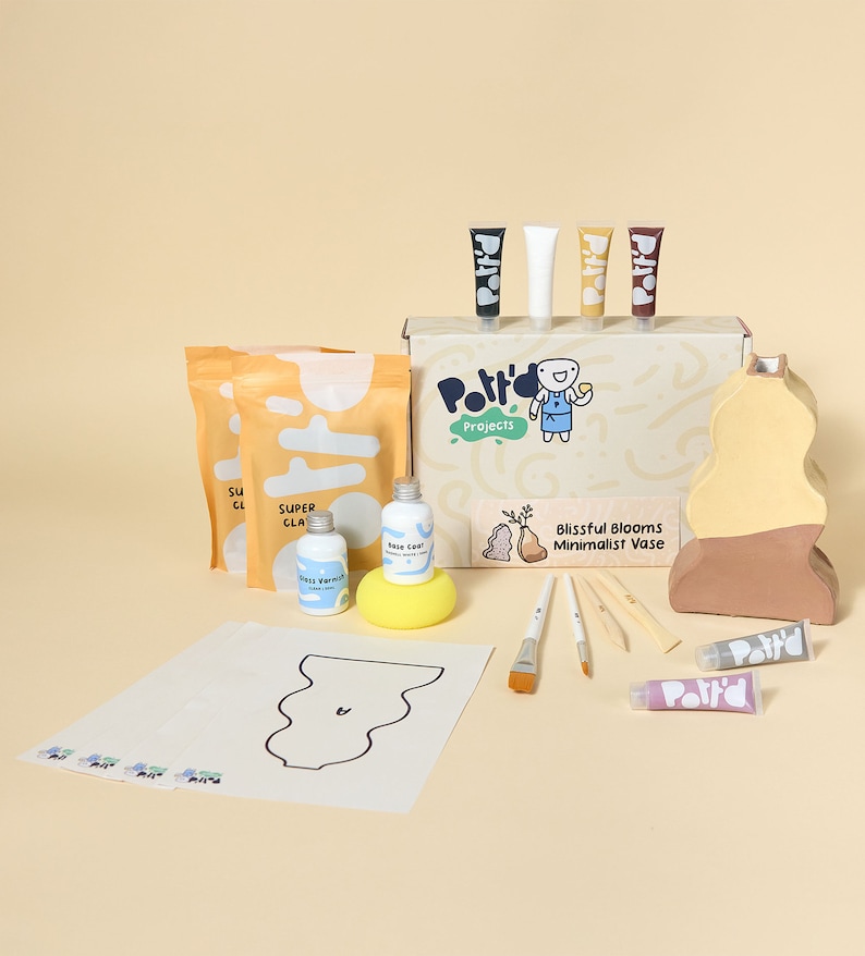 May include: A pottery kit for making a vase. The kit includes clay, paint, brushes, and a template. The vase is a minimalist design with a light brown and yellow color scheme. The box says "Blissful Blooms Minimalist Vase".