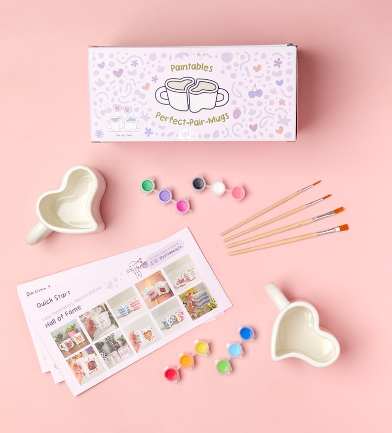 Puede incluir: Un kit de tazas para pintar con tazas en forma de coraz&oacute;n, botes de pintura y pinceles. El kit incluye una caja con el texto "Paintables Perfect-Pair-Mugs". Tambi&eacute;n se incluye una gu&iacute;a con im&aacute;genes de tazas pintadas.
