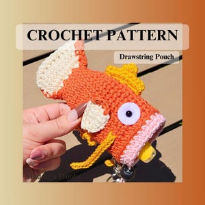 May include: Crochet pattern for a drawstring pouch shaped like a cartoon fish. The fish is primarily orange with cream, yellow, and pink accents. The text "CROCHET PATTERN" and "Drawstring Pouch" are displayed on the image.