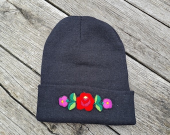 Puede incluir: Gorro negro con un diseño floral bordado en rojo, rosa y verde.