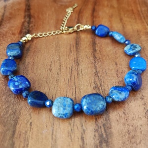 Op de afbeelding: Een blauwe edelsteen armband met een gouden ketting sluiting. De armband is gemaakt van vierkante lapis lazuli kralen.