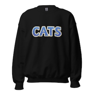 May include: Black sweatshirt with the word "CATS" in large, blue, polka-dotted letters outlined in a cream color. The sweatshirt is a crew neck style and appears to be made of a soft material.