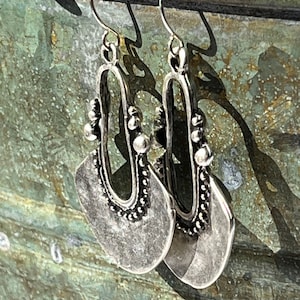 May include: A pair of silver dangle earrings with a teardrop shape and beaded accents.