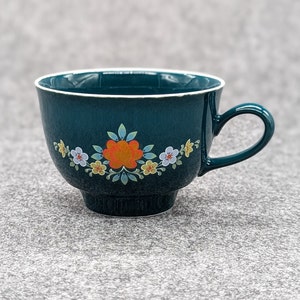 Könnte beinhalten: Eine teeblaue Teetasse mit weißem Rand und Blumenmuster. Die Blumen sind orange, gelb und weiß.