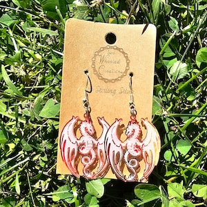 May include: A pair of red dragon earrings with sterling silver hooks. The earrings are on a brown card with the text "Two Wheeled Creations" and "Sterling Silver".