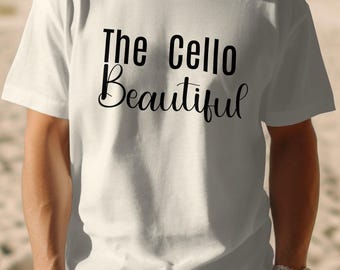 May include: White t-shirt with the text "The Cello Beautiful" in black script. The shirt is short-sleeved and appears to be made of cotton. The person wearing the shirt is standing on a sandy beach.