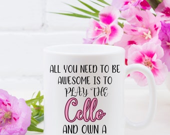 May include: White ceramic mug with black text that reads "All you need to be awesome is to play the Cello and own a cat". The word "Cello" is in pink.