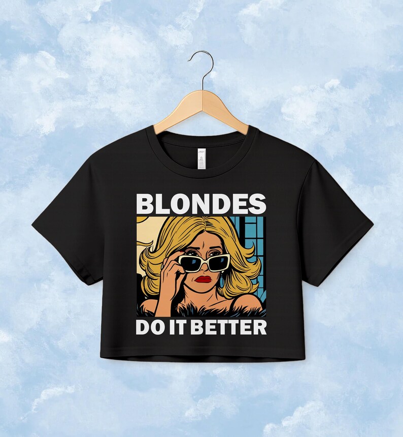 Pu&ograve; includere: Una t-shirt corta nera con una grafica pop art di una persona bionda che indossa occhiali da sole e rossetto rosso. Il testo sopra la grafica recita BLONDES e il testo sotto recita DO IT BETTER in lettere maiuscole bianche e in grassetto.