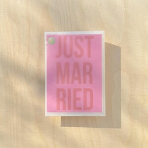 May include: A pink card with the text "JUST MARRIED" in white letters.