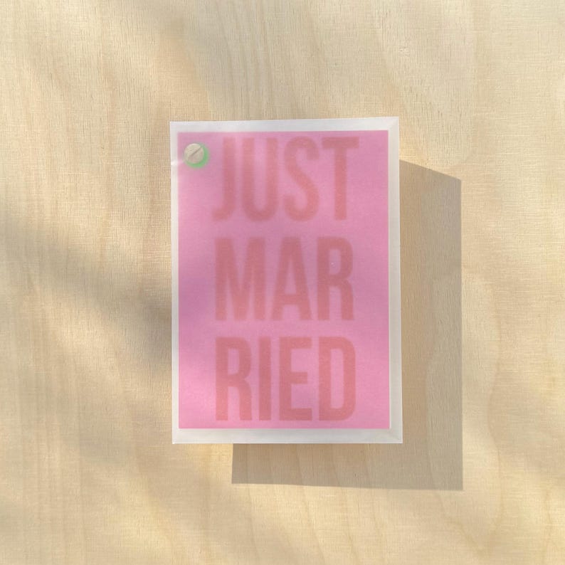 May include: A pink card with the text "JUST MARRIED" in white letters.