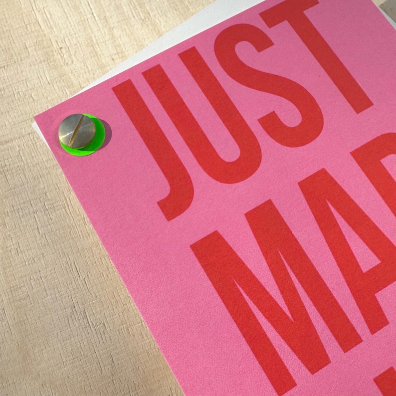 May include: A pink card with the word "JUST" in large red letters. A silver screw is attached to the card with a green plastic washer.