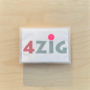 May include: A white card with the text "4zig" in gray letters and a pink circle above the text.