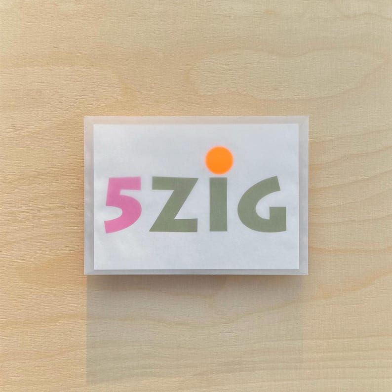 May include: A white card with the text "5ZIG" in pink and green letters. A small orange circle is above the text.