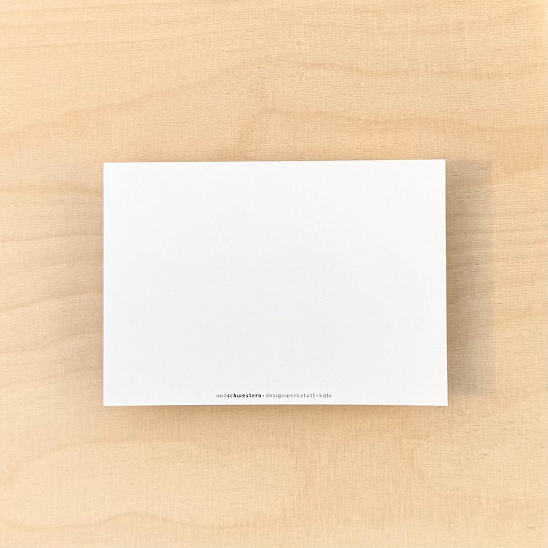May include: A blank white card with the text "undekorwustern - designwerkstatt - k&ouml;ln" printed in black at the bottom.