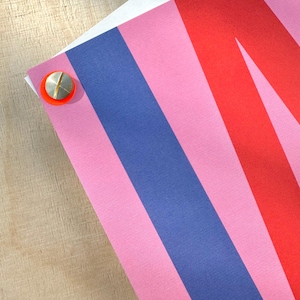 May include: A close-up of a colorful striped fabric with pink, red, and blue stripes. The fabric is textured and has a slight sheen.
