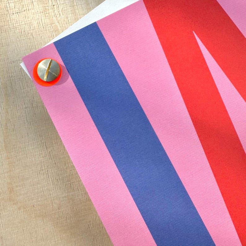 May include: A close-up of a colorful striped fabric with pink, red, and blue stripes. The fabric is textured and has a slight sheen.