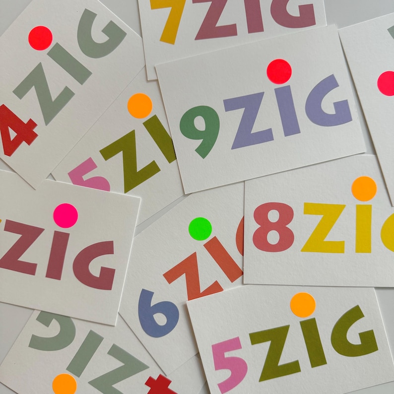 May include: A collection of colorful cards with the word "zig" printed on them. Each card features a different number from 4 to 9, with a bright colored dot next to the number. The cards are arranged in a random pattern.