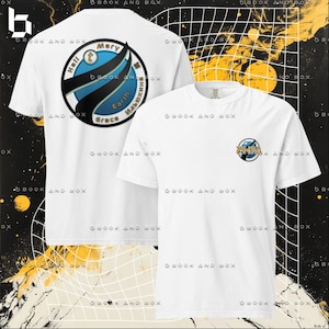 Puede incluir: Dos camisetas blancas. Una tiene un gráfico circular grande con el texto "Hell Mary Earth Grace" en la espalda. La otra tiene una versión más pequeña del mismo gráfico en la parte delantera.