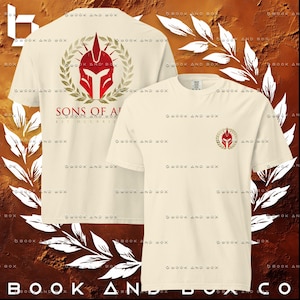 May include: Cream-colored t-shirts with a red and gold Spartan helmet design. One shirt features the design on the front and back, with the text "SONS OF A" and "MDCCXXI". The other shirt has a smaller helmet design on the front.