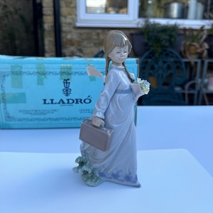 A Boxed Lladro 7604 School Day Porcelain Figurine of A Girl Holding Flowers in One Hand While Carrying A School Briefcase in Other Hand