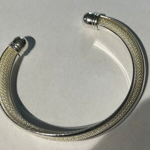 Può includere: Un braccialetto rigido in argento con finitura testurizzata e estremità arrotondate.