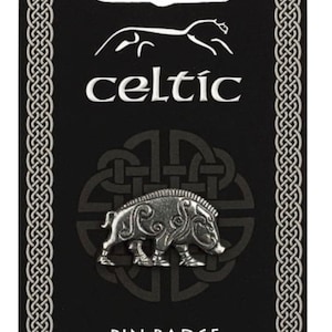 Könnte beinhalten: Ein silberfarbener Ansteck-Pin mit einem detaillierten Wildschwein-Design auf schwarzem Hintergrund. Das Wort "celtic" ist weiß dargestellt, mit einem keltischen Knotenmuster und dem Schriftzug "PIN BADGE" darunter.