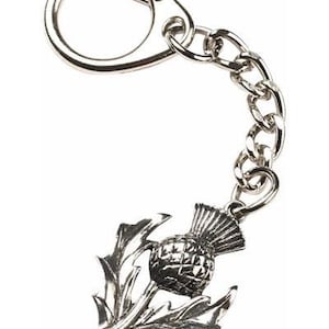 May include: A silver keychain featuring a detailed depiction of a Scottish thistle, a national symbol of Scotland. The keychain has a silver ring and a silver chain.
