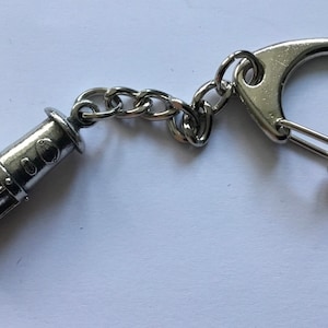 Könnte beinhalten: Silberner Schlüsselanhänger mit einer Miniatur-Nachbildung einer Grubenlampe.